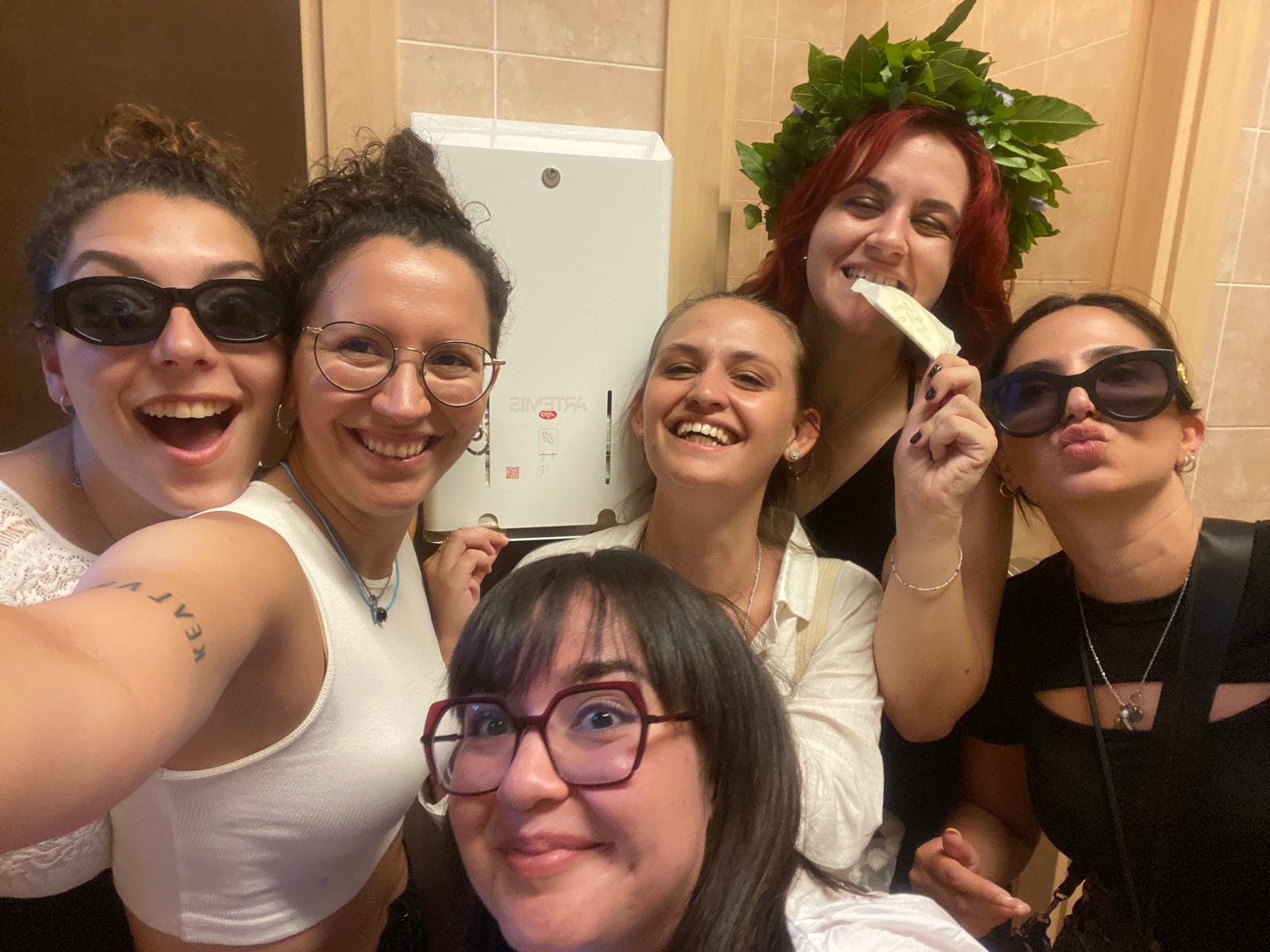 studentesse sorridenti davanti a un distributore di assorbenti