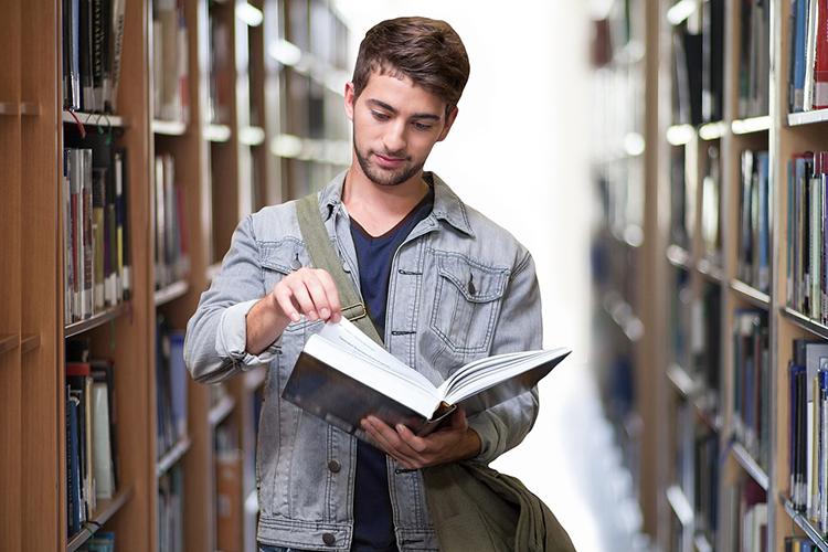 ragazzo che sfoglia un libro in biblioteca